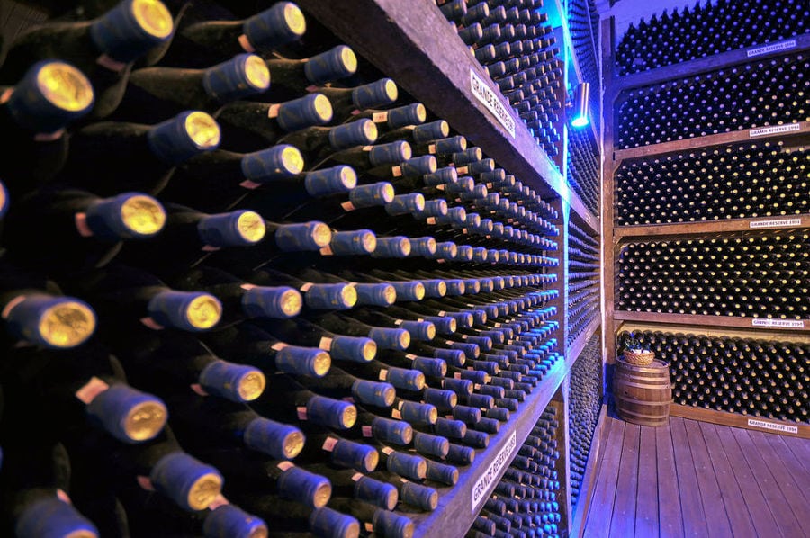 stacked bottles on top of each other in the storage lockers at illuminated 'Vaeni Naoussa' cellar