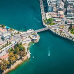 Aerial view of a vibrant city featuring a prominent bridge and a bustling harbor, showcasing urban life and waterways.