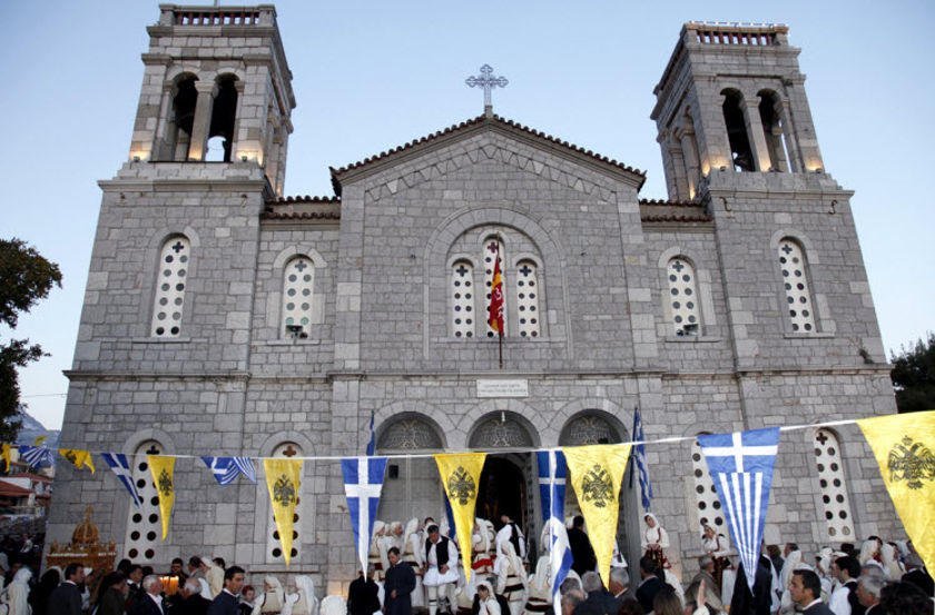 People outside at front at church of Agios Georgios (Saint George) at Arachova, Greece that commemorate festival of her birth surrounded by trees