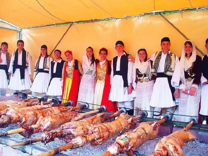 lambs skewered on metal rods on grilled and people dressed with folklore cloths watching them at Easter in Tripoli, at Arcadia Prefecture