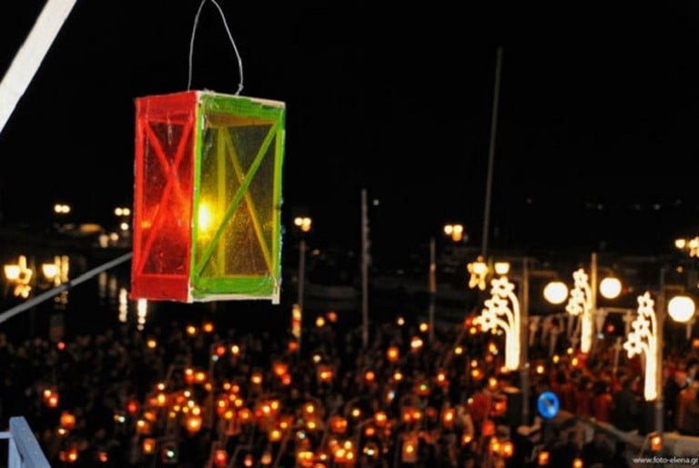 people front the church and holding illuminated lamps at The “Fanarakia” (lanterns) of Tinos, Greece by night