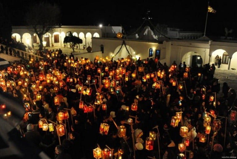 people front the church and holding illuminated lamps at The “Fanarakia” (lanterns) of Tinos, Greece by night