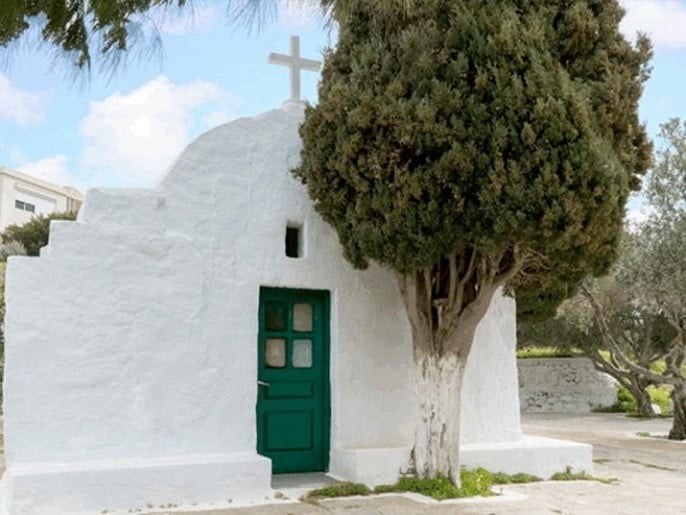 entrance of the Church of Virgin Mary the Faneromeni with a tree in the front and commemorate festival of her birth at Milos, Trypiti, Greece