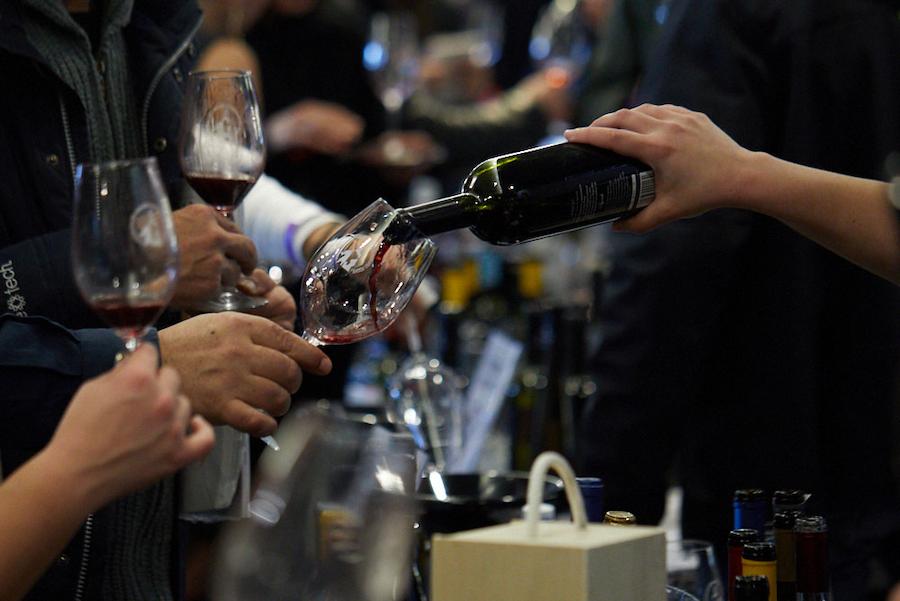 woman pouring wine in glasses from the bottle at PELOPONNESE WINE FESTIVAL