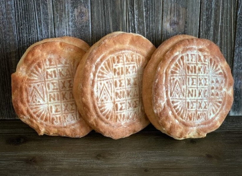 Three artoklasia means engraved personalized round breads sating vertical on wood surface