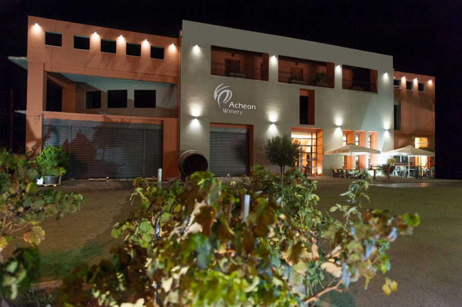 illuminated front side of the building at night that says 'ACHEON WINERY' on the wall