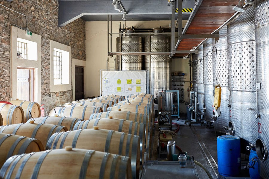 Gaia Wines Santorini plant with wood barrels on the ground and aluminum wine storage tanks on the one side