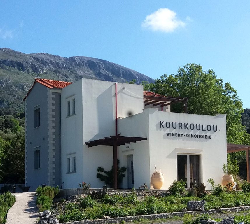 building's entrance that says 'KOURKOULOU WINERY' with ceramic pots on both sides