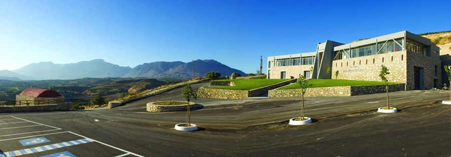 'Domaine Zacharioudakis' stone building seen from the front and the entrance has lawn green and steps on both sides