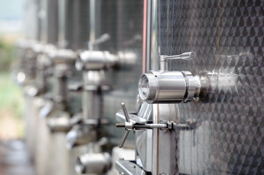 view of base of lying aluminum wine tanks with doors' handles at 'Tsililis' plant