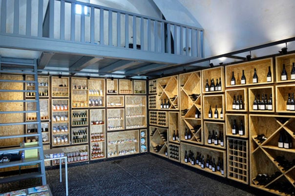 corner with wooden shelves with wine bottles and stairs leading to an indoor balcony at 'Venetsanos Wine Museum'