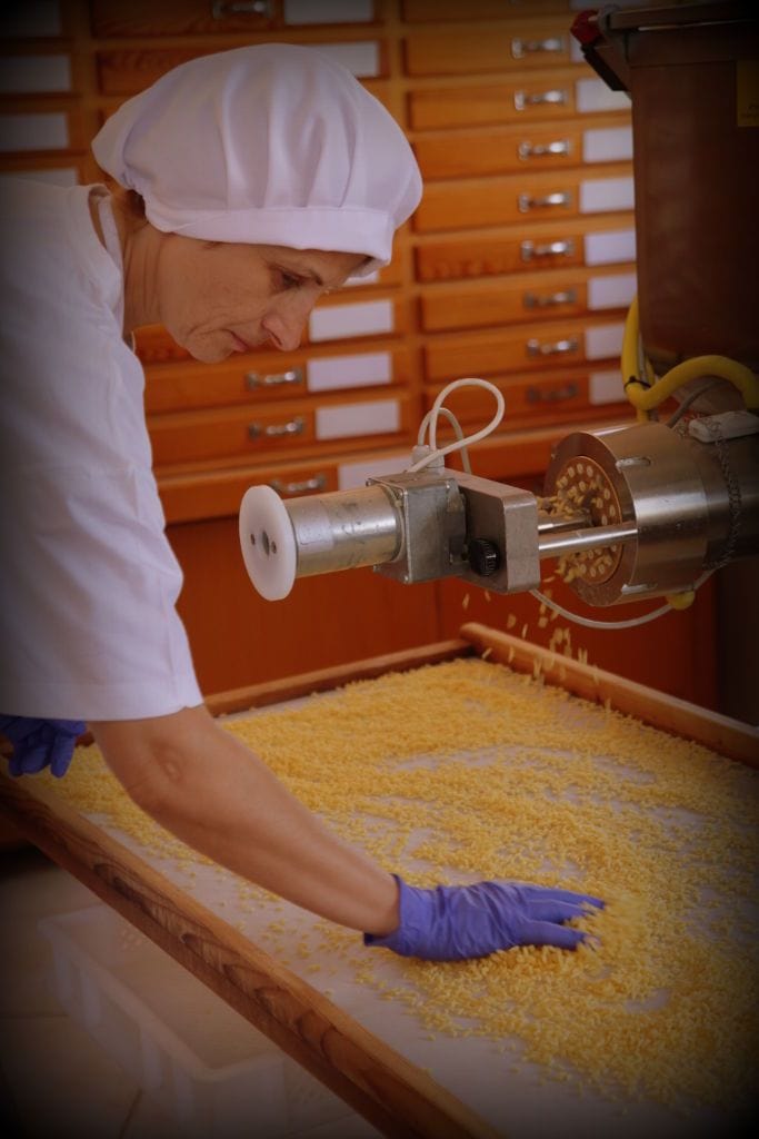 woman putting pasta from pasta production machine on the wood frame at 'Dardouma family