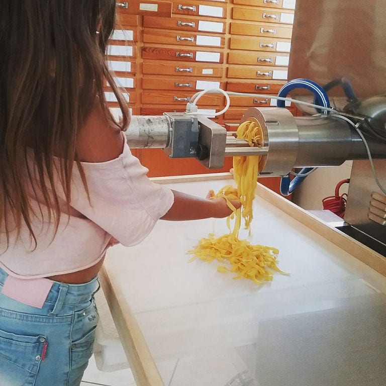 woman putting pasta from pasta production machine on the wood frame at 'Dardouma family'