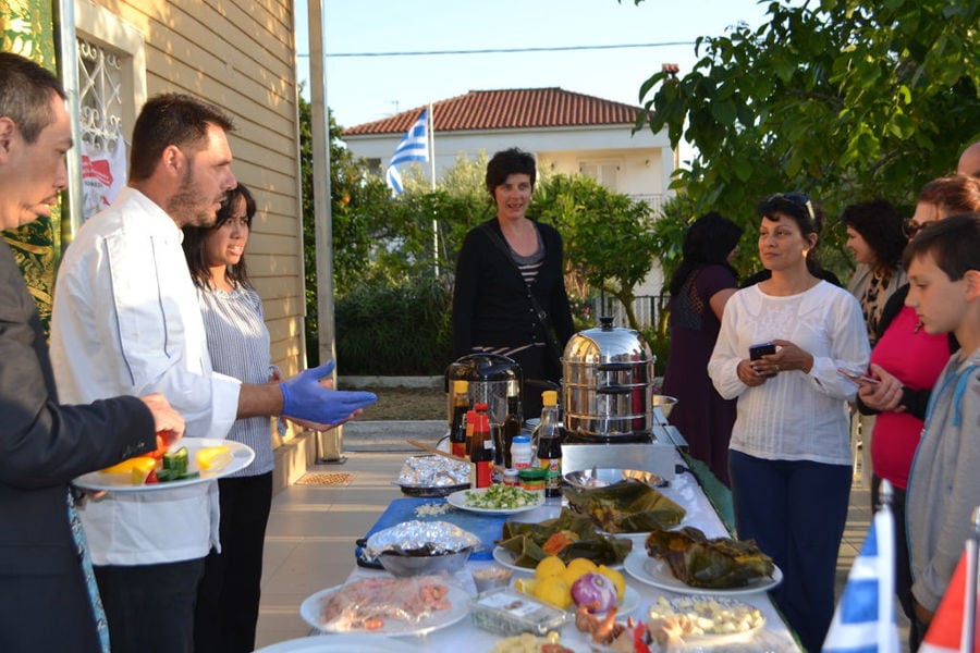 chef presenting a lot of delicious foods and a group of tourists listening at En Kefallinia Organic Farm Restaurant garden