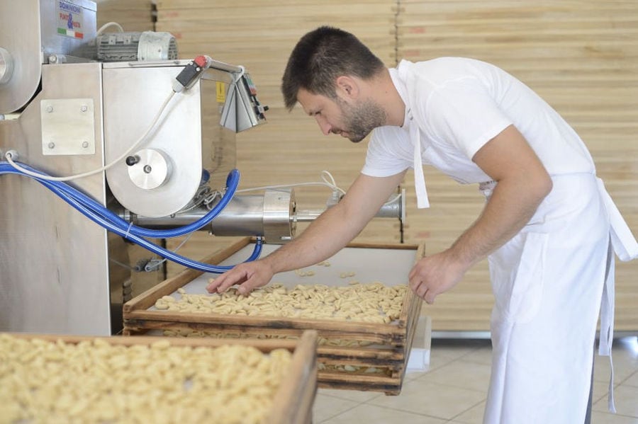 man putting pasta from pasta production machine on the wood frame at 'Dardouma family'