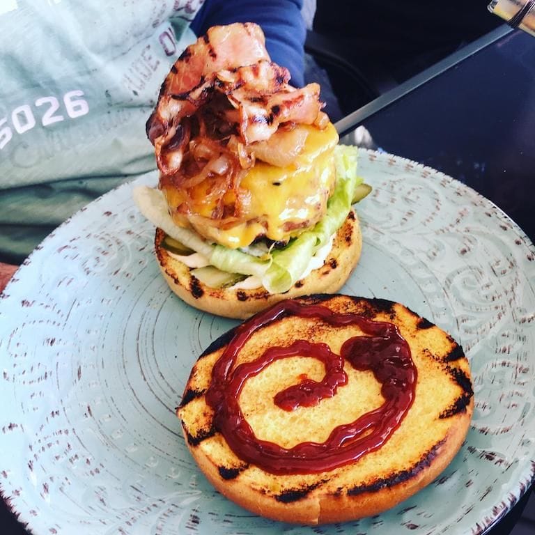 2 slices of bagel, fried, one of them with ketchup and the other with salad, fried bacon, sauce at Savor Nafplio