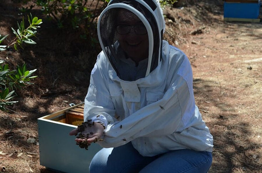 woman beekeeper holding bees at 'Melissavet' and showing at the camera