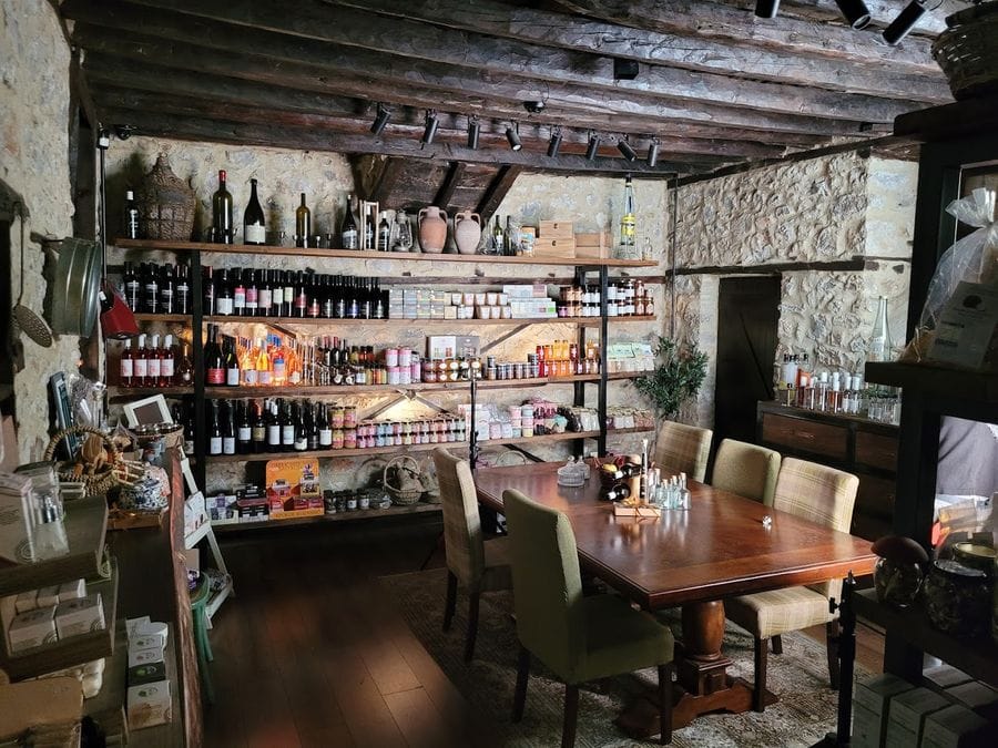 An inviting indoor area of a stone café featuring a large wooden table with five chairs. In the background, a prominent ledge showcases the café's enticing products.