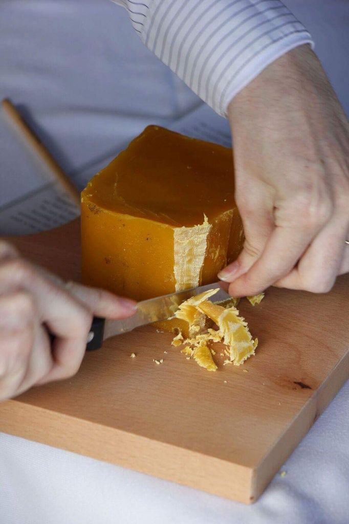 woman cutting with a knife a piece of natural bee wax from 'Gea Olympou'