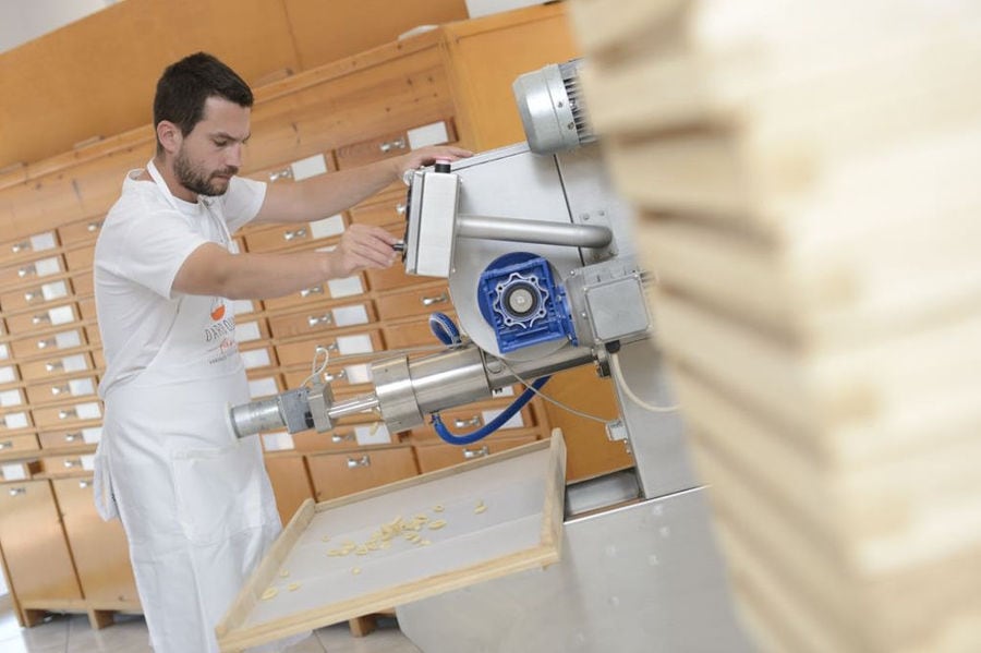 man dressed with t shirt that says 'DARDOUMA family' working pasta production machine