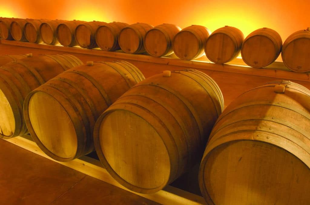 lying wooden barrels in a row at ‘Domaine Zacharioudakis’ cellar that recognized with many awards|