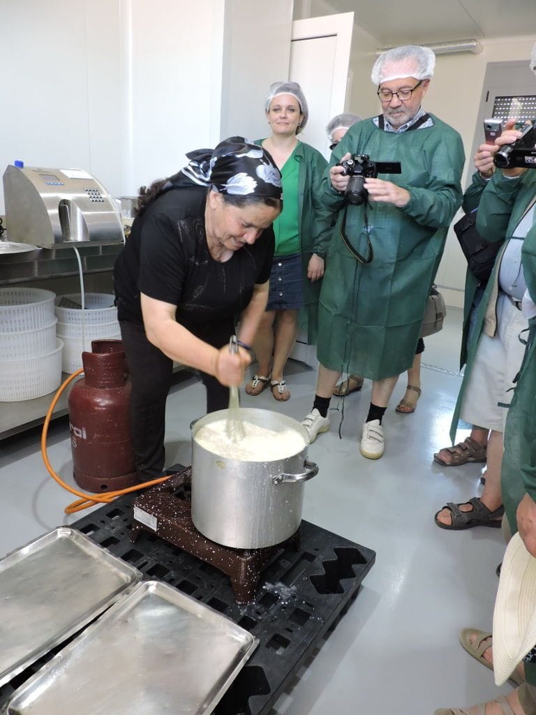 tourists taking photos with the camera a woman that mixing with a hand mixer the composition boiling in the pot at 'Galeni' plant