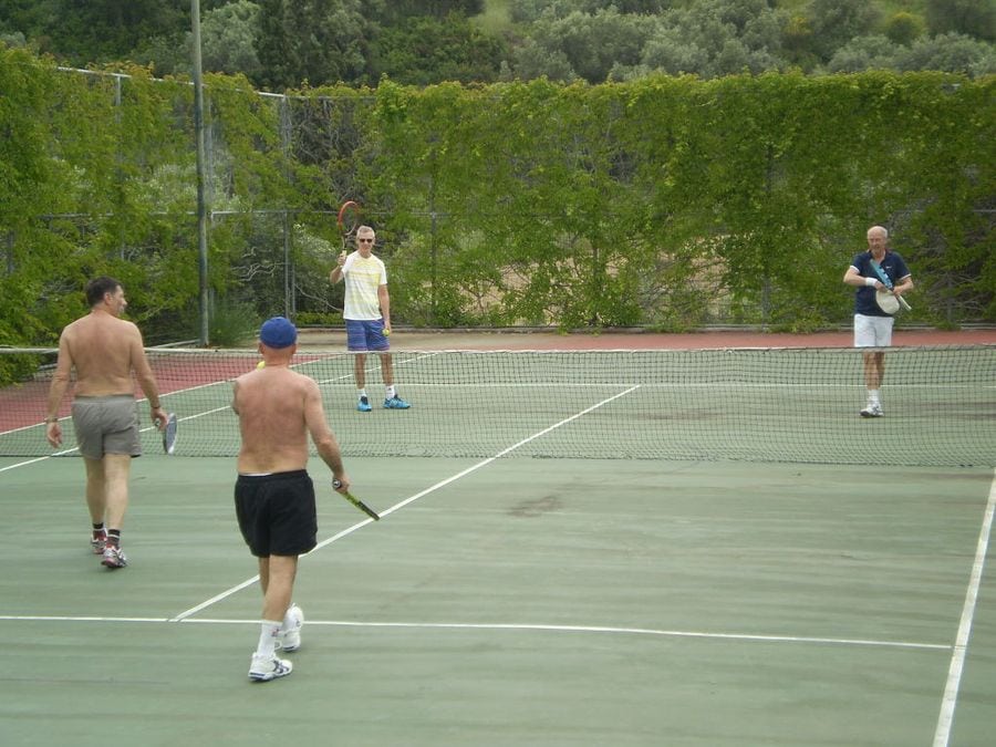 four men playing tennis on 'Vateri Guest House' tennis court