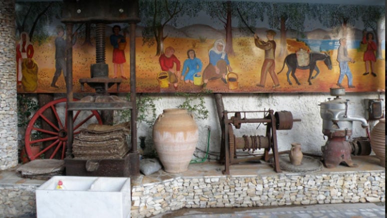 ceramic pot and old grape press at Zahaios winery background of painting mural on the wall with people picking grapes