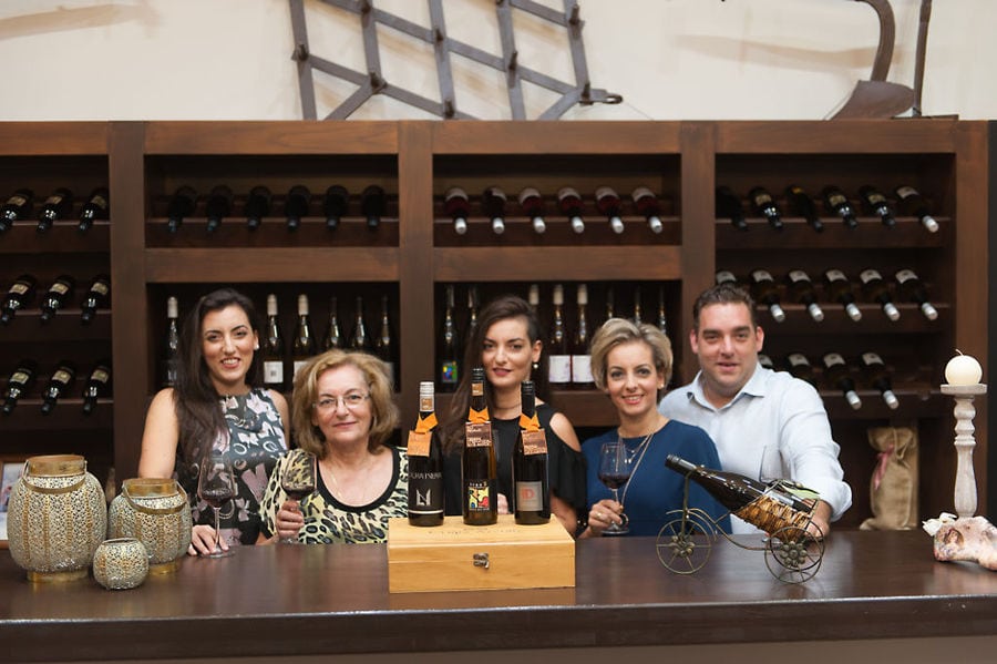 the owners of 'Ancheon Winery' standing behind a bar full of wines