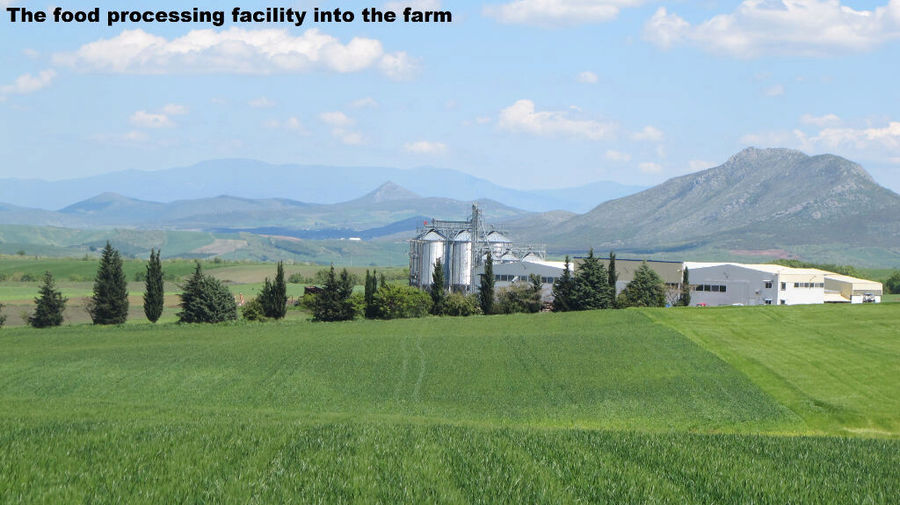 far view of Antonopoulos Farm plant surrounded by green crops and mountains in the background