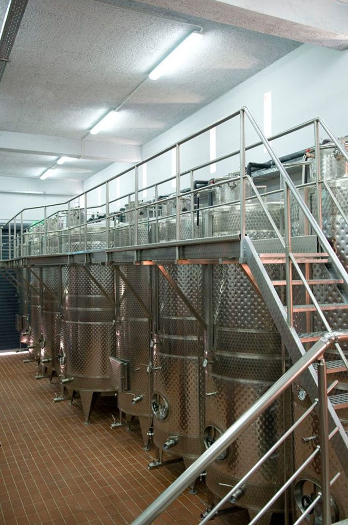 a metal ladder on the top of lying aluminum wine storage tanks with at 'Domaine Zacharioudakis' plant