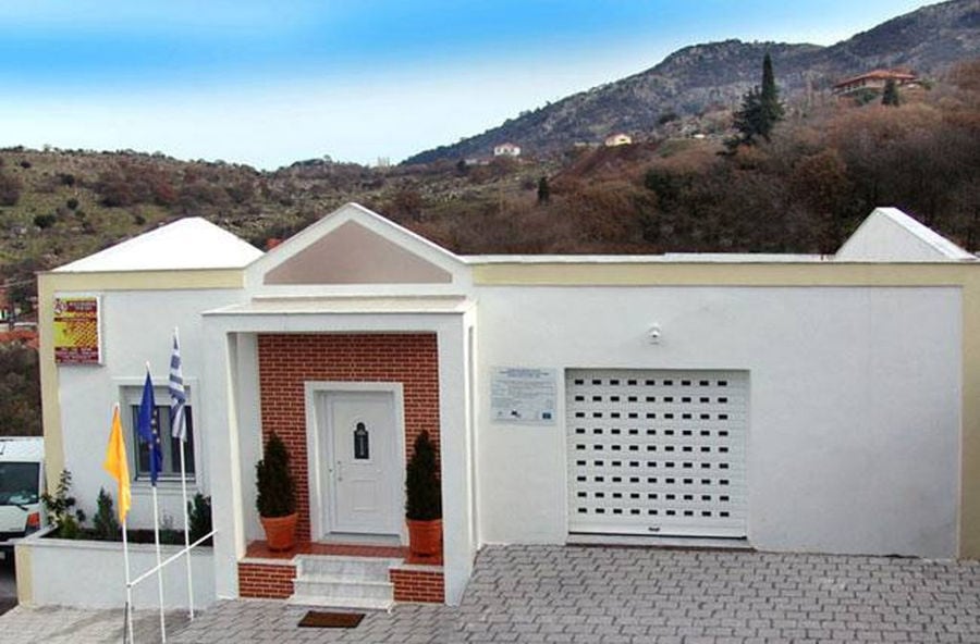 front view of Melostagma building with three flags close to entrance and hills in the background
