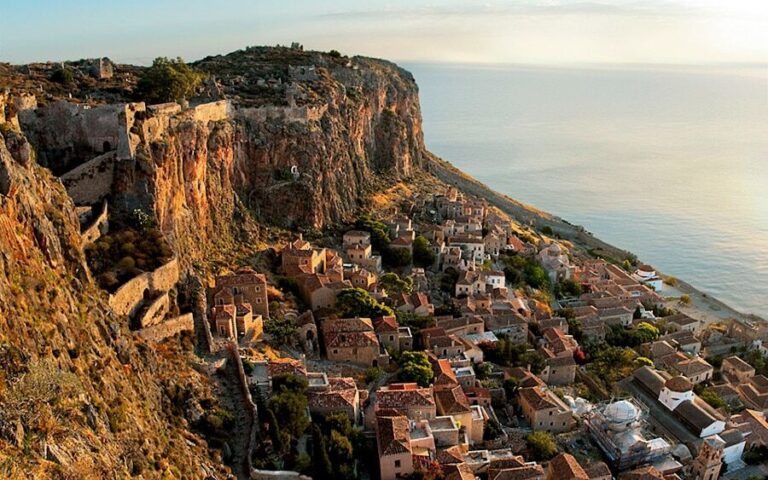 a fortress-town on the hill with the sea in the background