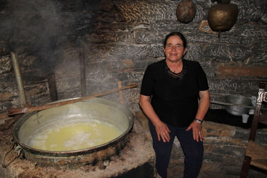 woman is by the cauldron and smiling happily at the camera at 'Galeni' farm