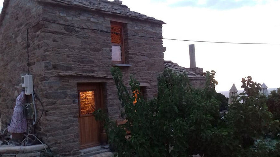 illuminated 'Melissavet' stone building with tree in the front