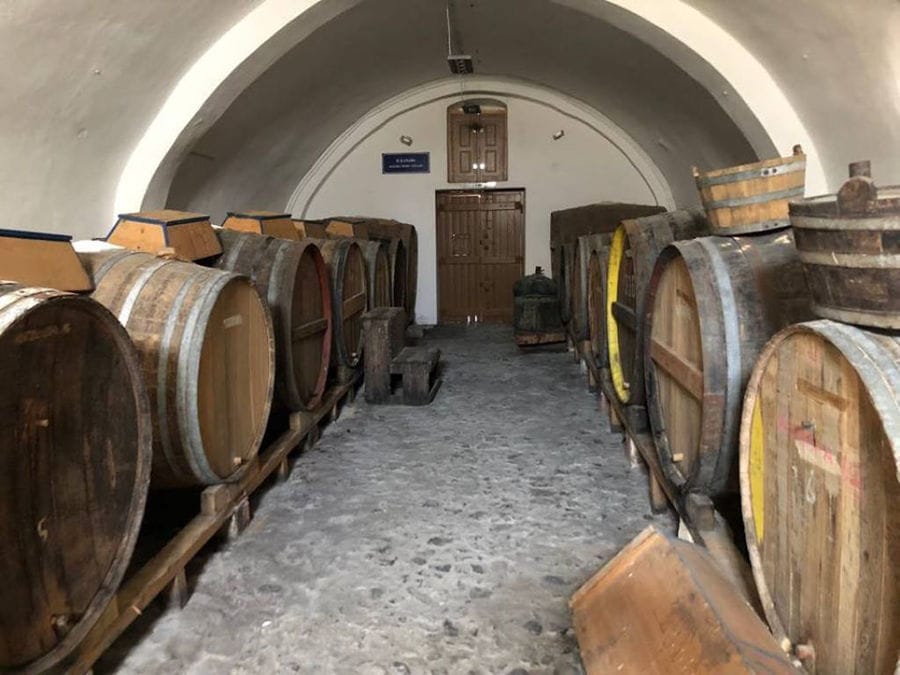 lying wooden barrels in a row at Tselepos Winery cellar with arcade