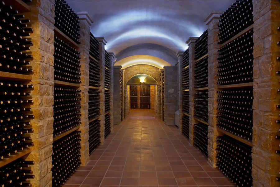 stacked bottles on top of each other in the walls of illuminated 'Wine Art Estate' cellar