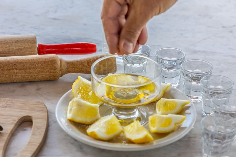 A glass filled with an enticing alcoholic beverage takes center stage, surrounded by fresh lemon slices on a small plate, offering a visually appealing and refreshing combination that tempts the taste buds.