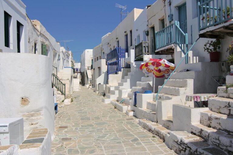 pavement street at Chora of Folegandros with white houses and blue windows on the both sides