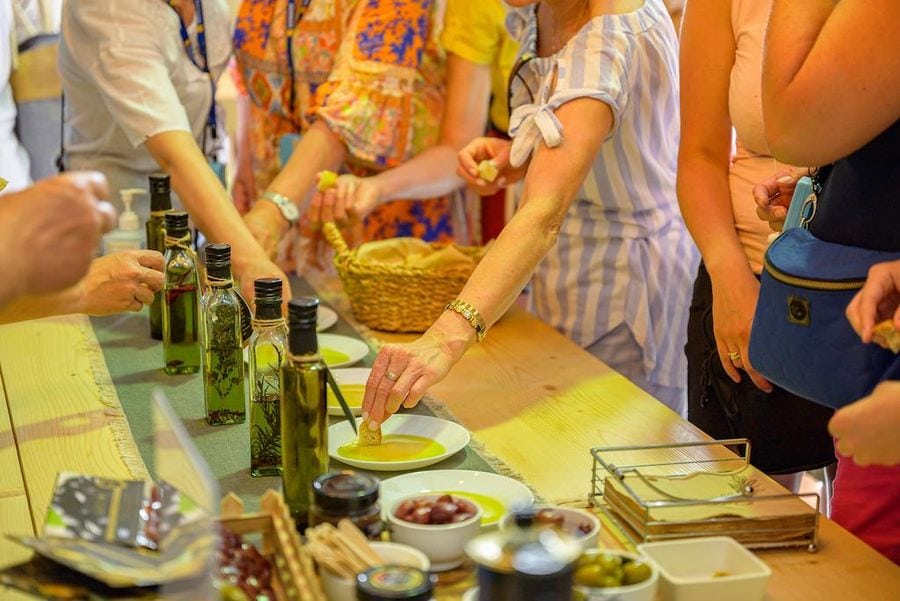 Close-up of tourists tasting olive oil with bread around the table at Oilympian Koufolias