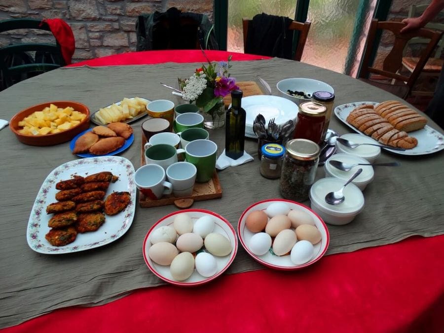 Table adorned with grey and red, featuring eggs, bread, zucchini balls, omelette.