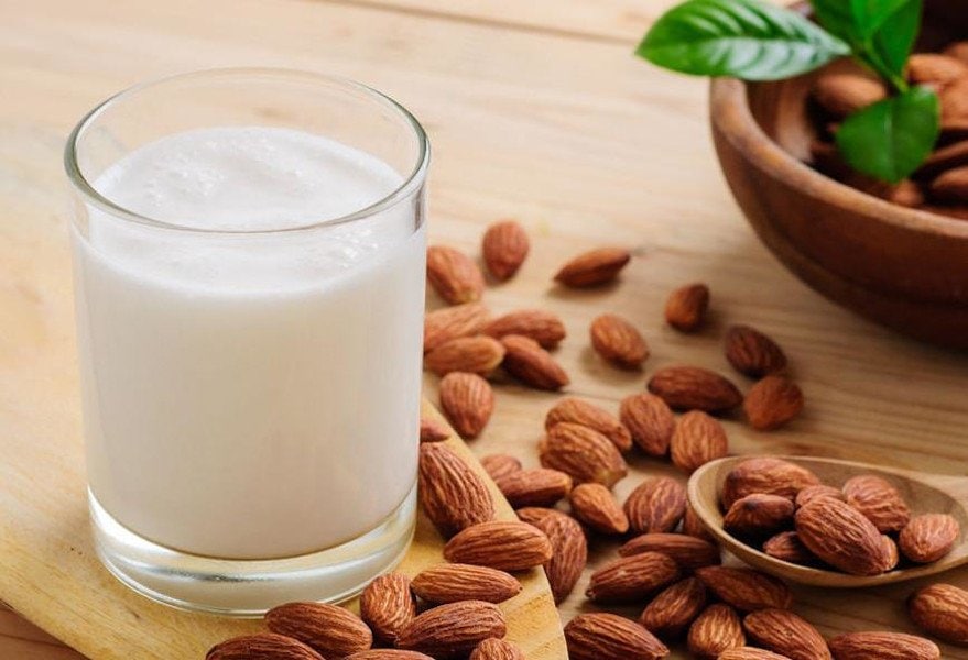 Close-up of glass with Greek ‘dasogalo’ a white beverage surrounded by shelled almonds