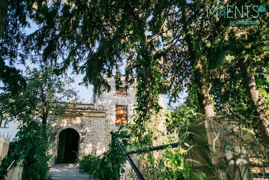 Dourakis Winery stone building in the background of trees in the sunshine