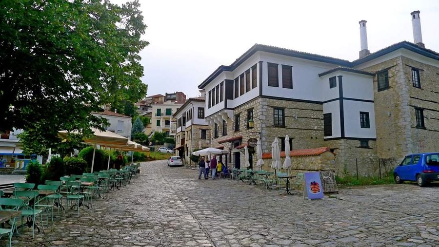 A rustic stone café with outdoor seating, tables, and chairs. Each table adorned with an umbrella, providing shade and a cozy ambiance for guests.