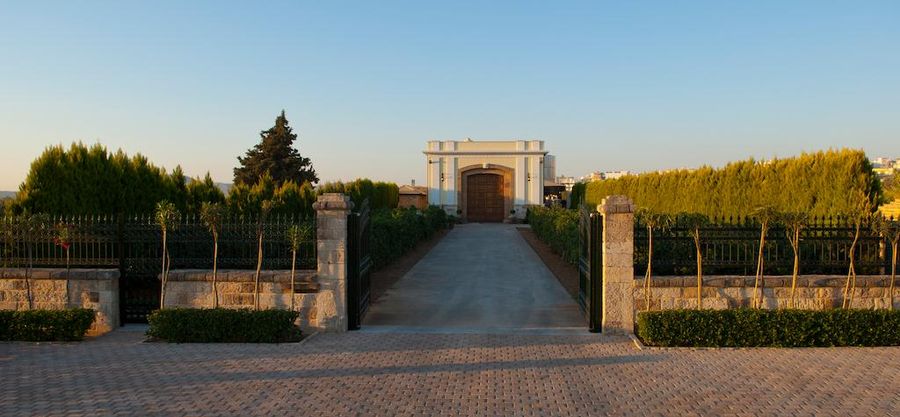 Gikas winery building seen from the front and the entrance has lawn green, fence and stone walkway