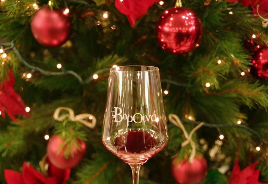 Glass with wine and said vorOina and christmas tree with red balls in the background