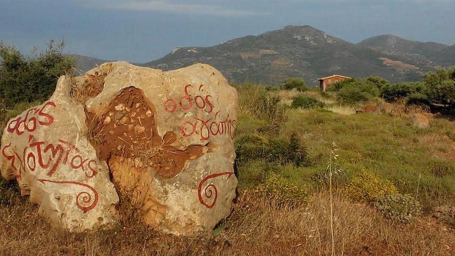 Greek words written on the big rocks at Korogonas Ark and mountains, trees and building in the background
