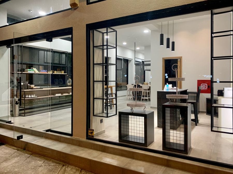 Sleek, modern kitchen in black and white hues, viewed through a plate glass, exuding contemporary elegance and inviting you to indulge in culinary delights.