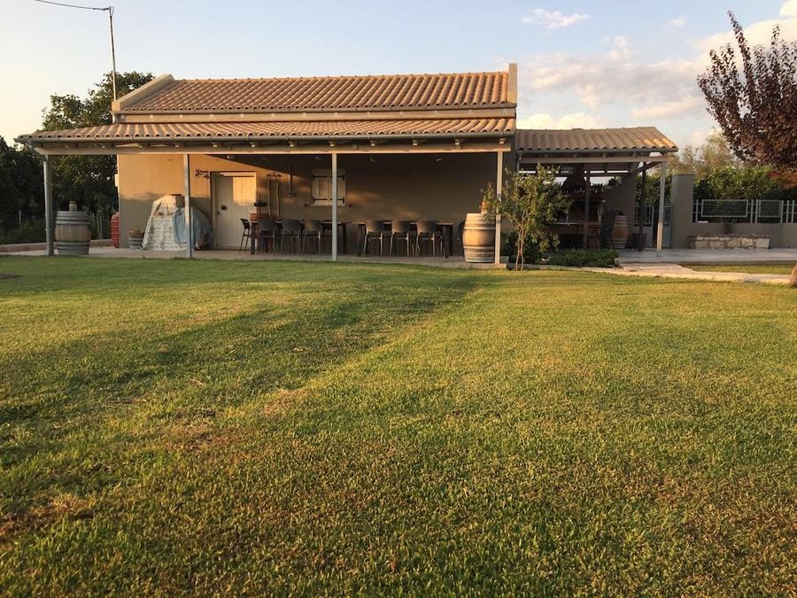 Jima winery small building with a big wood table and chairs outside and green grass in the front