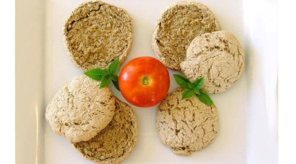 Close-up of round Greek ‘Kritharokouloura’ barley-based dry breads and a tomato between them
